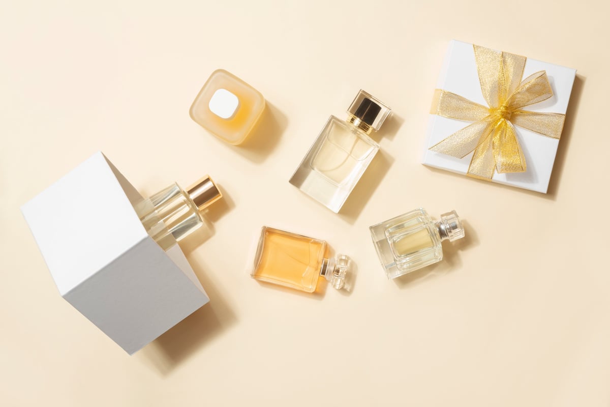 Frascos de perfume y caja de regalo en un arreglo plano sobre fondo beige