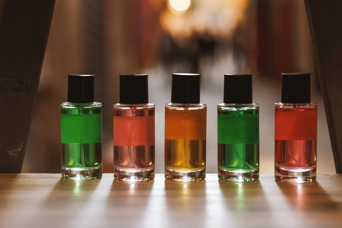 Cinco frascos de spray de vidrio con líquidos verde, rosa y naranja